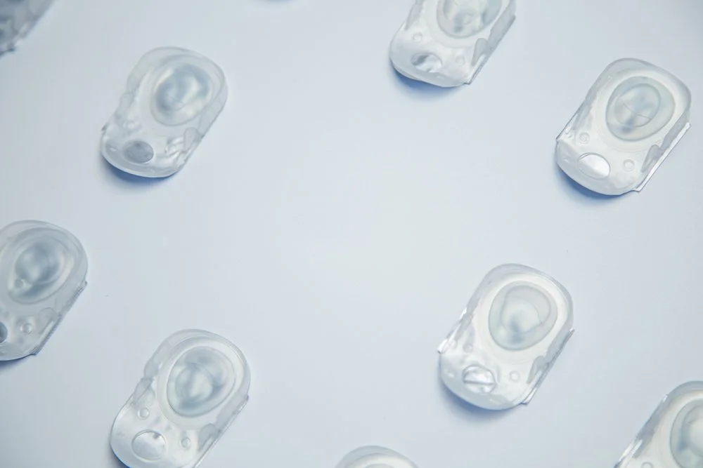 Clear plastic containers with round molds inside arranged in a circular pattern on a white surface.