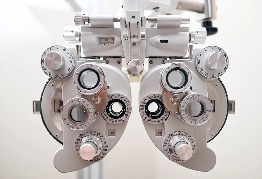 Close-up of a phoropter used by optometrists to test eyesight, with various dials and lenses.