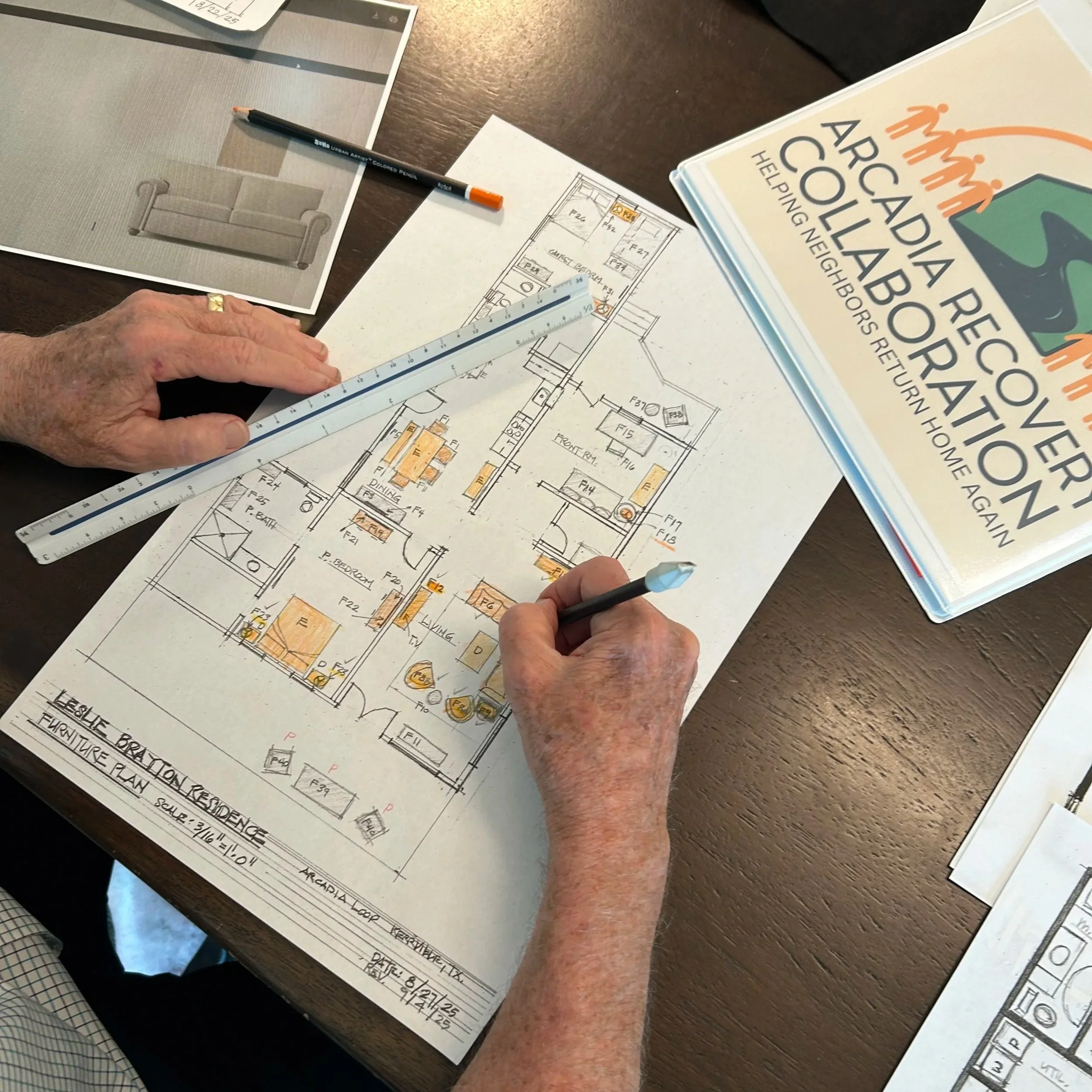 Image showing hands working on a home floor plan with a binder displaying the logo for "Arcadia Recovery Collaboration."
