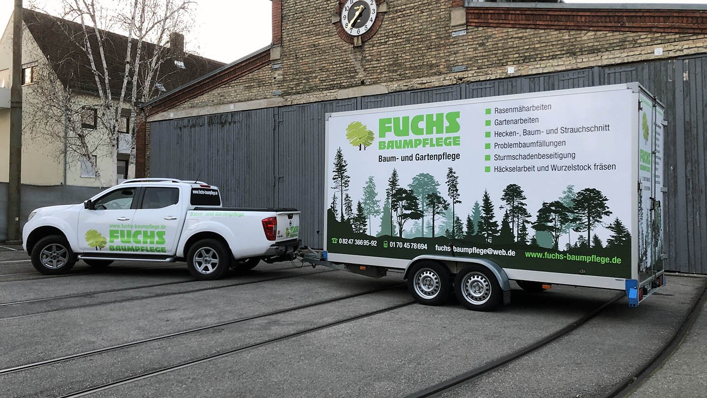 Ein weißes Fahrzeug der Firma Fuchs Baumpflege mit einem Anhänger. Der Anhänger hat eine große Beschriftung mit Baum- und Waldmotiven und Informationen zu Baumpflegeleistungen in deutscher Sprache.