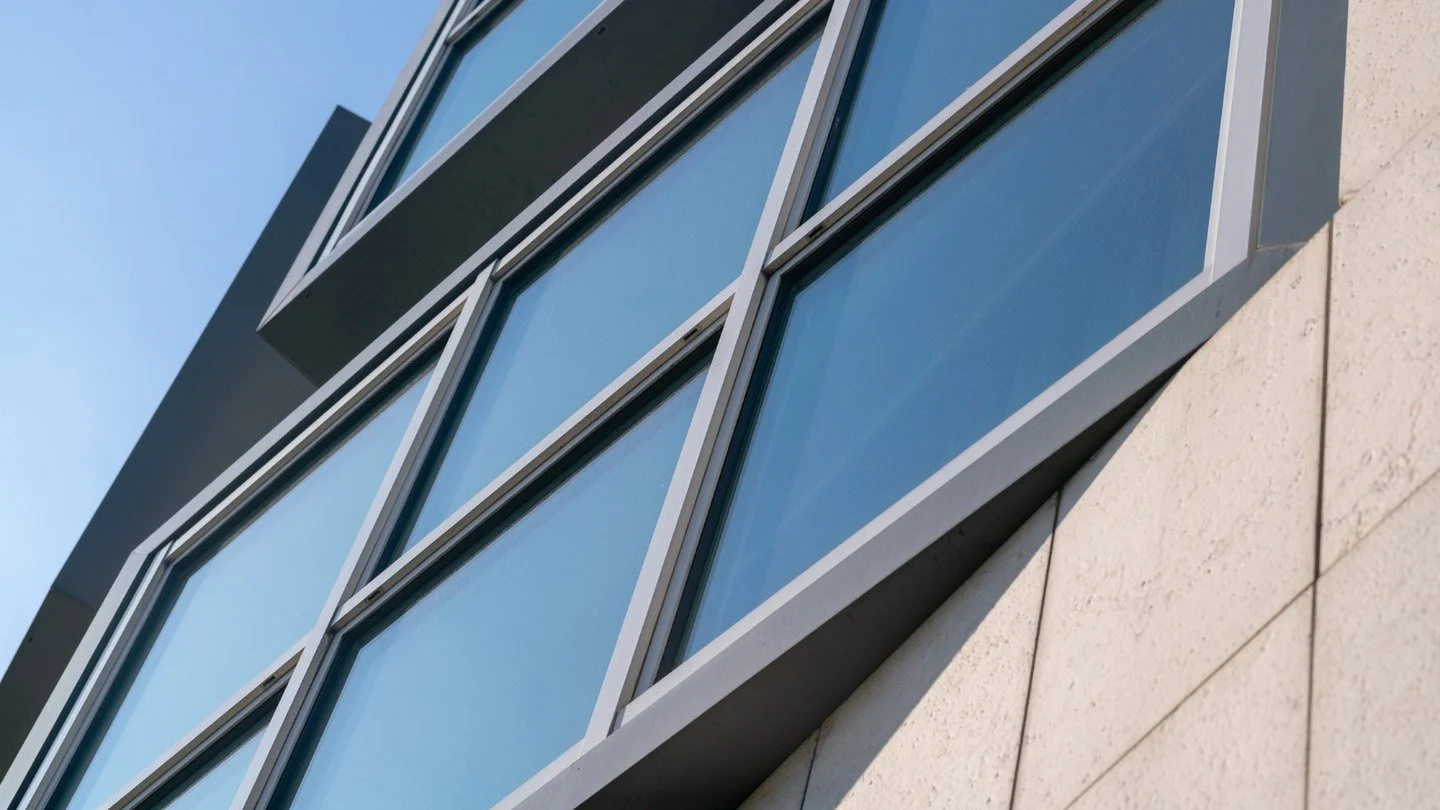 Moderne Gebäudefassade mit großen Glasfenstern und weißem Steinarmatur