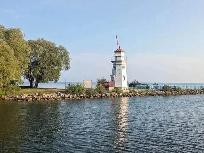 Lighthouse with US flag in Michigan's Obtawaing Biosphere Region.