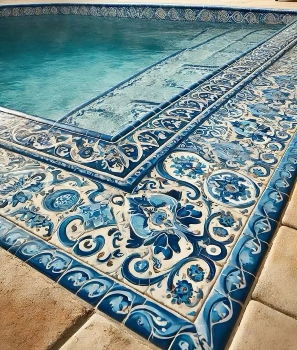 Borde de azulejos decorativos en tonos azules y blancos alrededor de una piscina con agua clarísima.