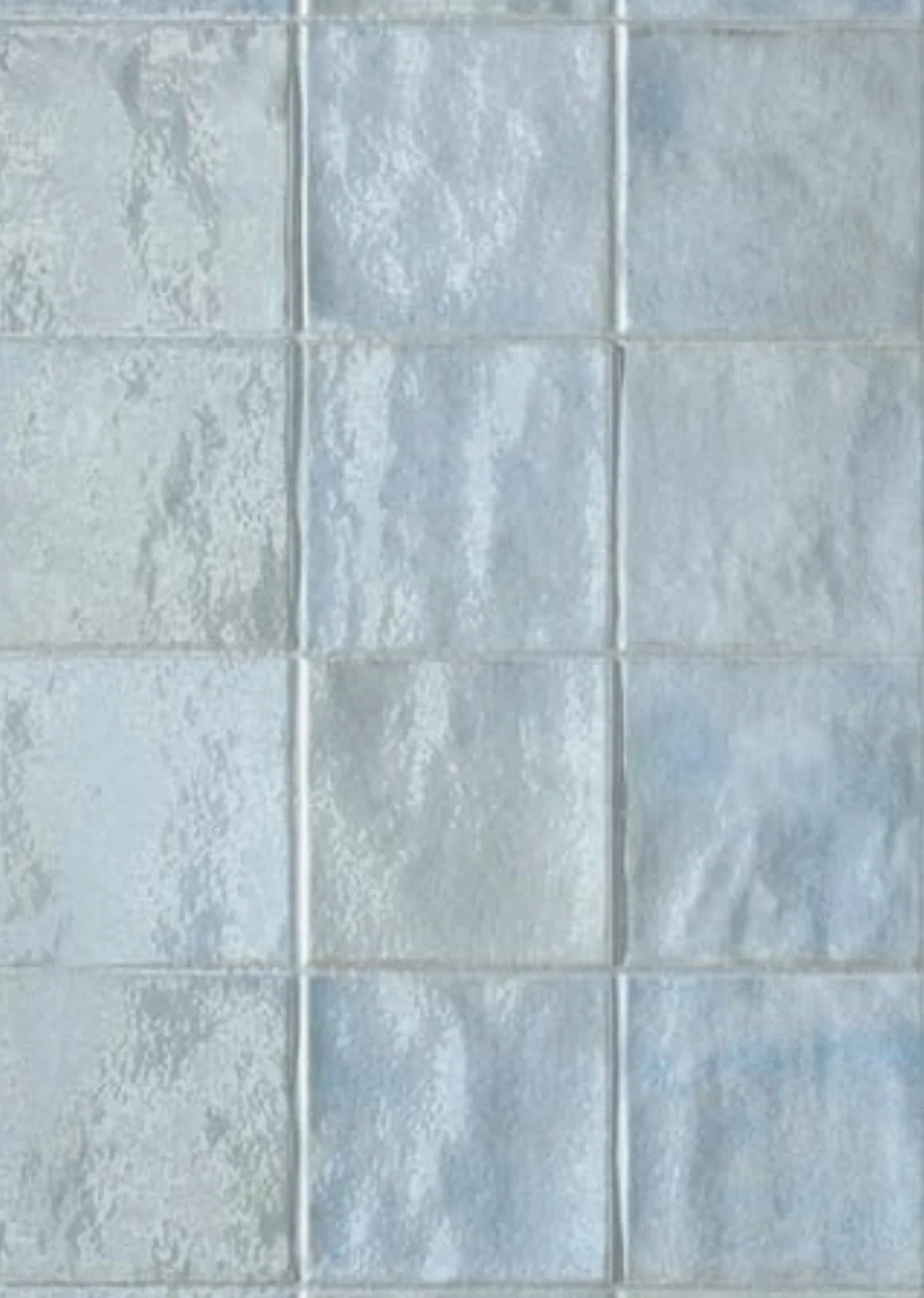 Revestimiento de azulejos blancos en una pared, con junta visible entre cada uno.