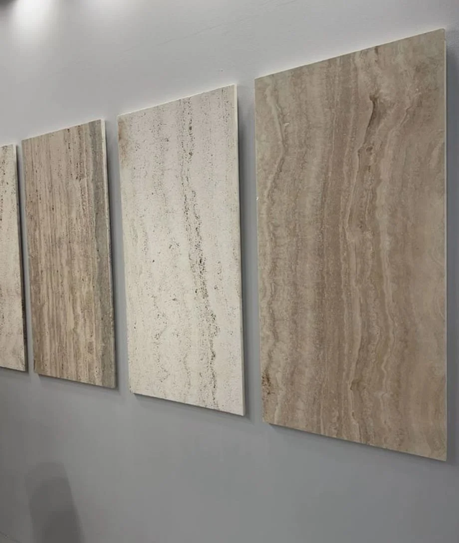 Cuatro placas de piedra en tonos beige y crema colgadas en una pared blanca.