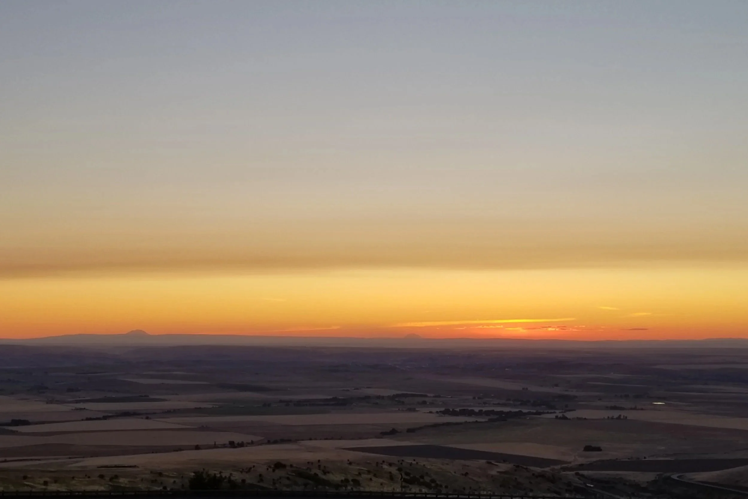 Vibrant orange, low sunset over a flat landscape.