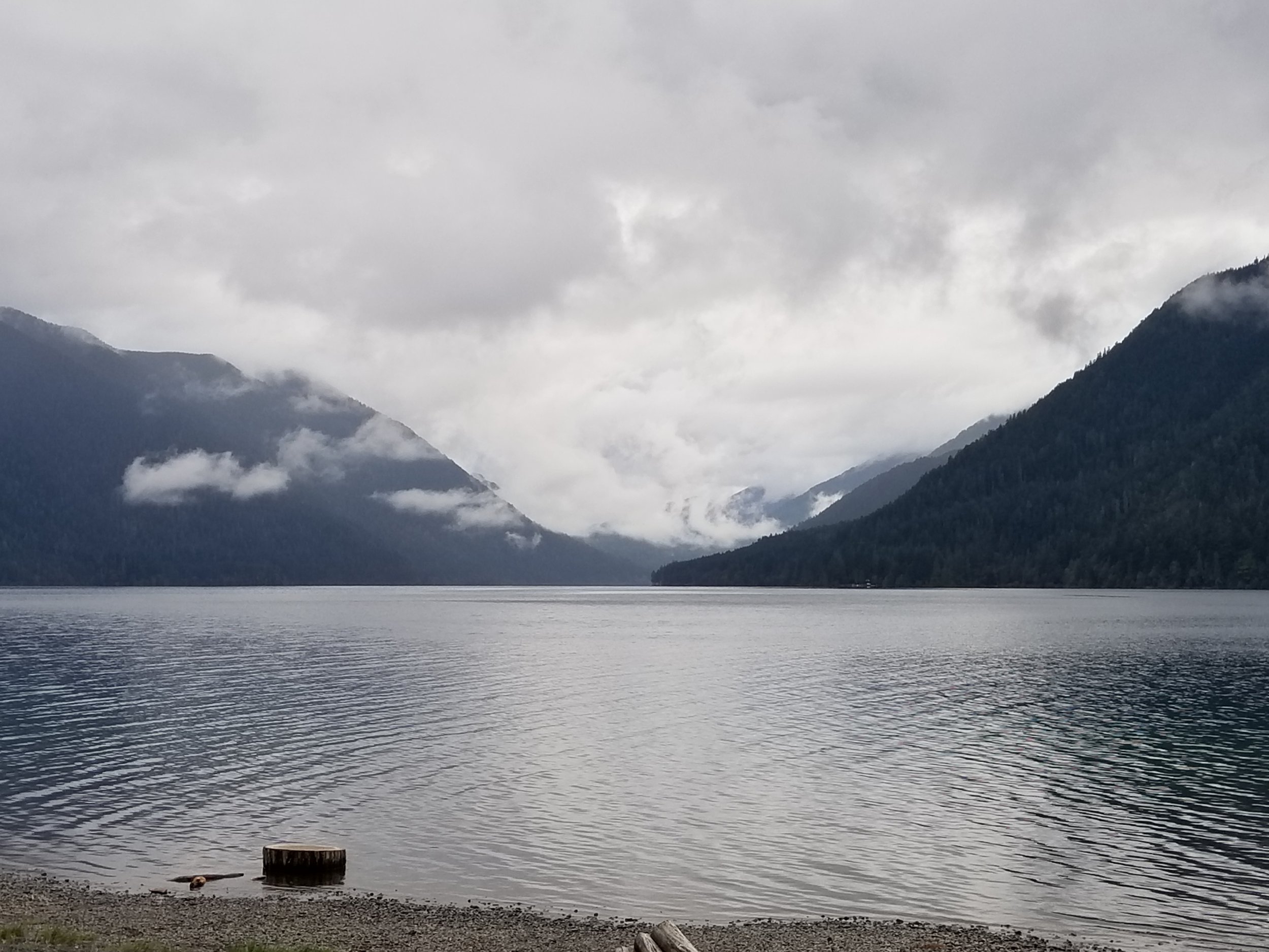 A dense fog gathers between mountain ranges above a crystal clear lake. The entire scene has the color of ice.