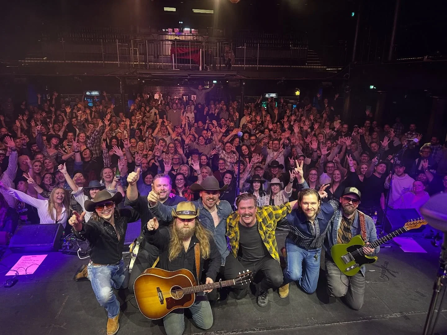 Musiker på scen efter ett framträdande med en stor publik i bakgrunden.