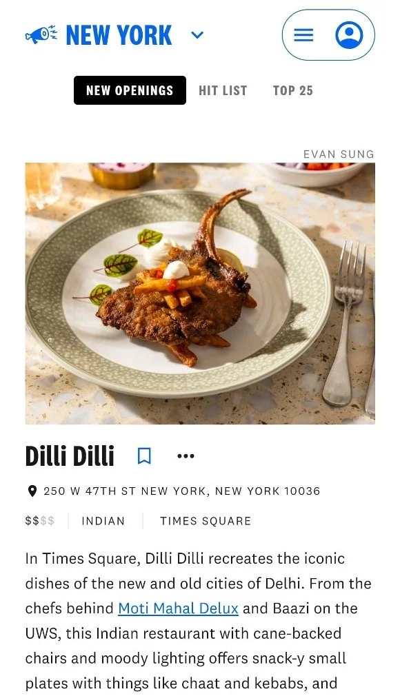 Close-up of a plate with a lamb chop garnished with vegetables, served on a patterned plate, with a fork to the right.