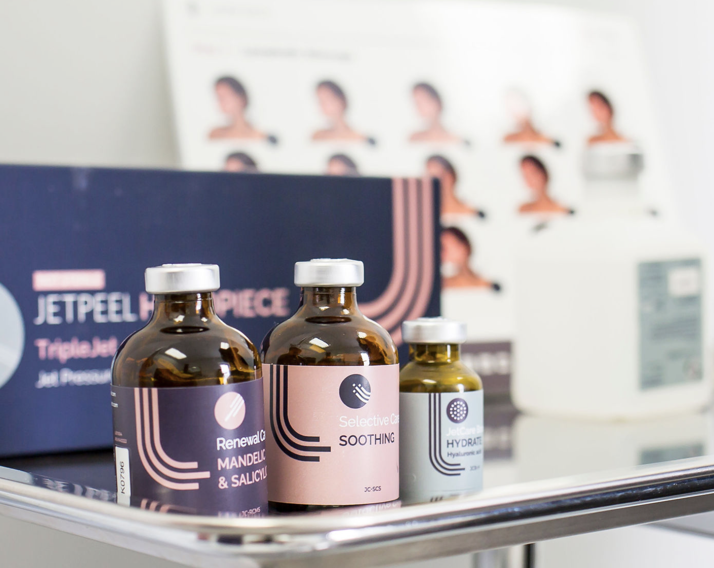 A tray holding three jars of skincare products labeled Renewal Complex, Selective Care, and Hydrate, with a skincare product box and a poster displaying various hairstyles in the background.