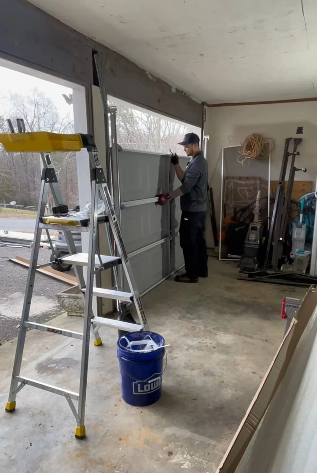A man working on installing or repairing a garage door inside a garage space.