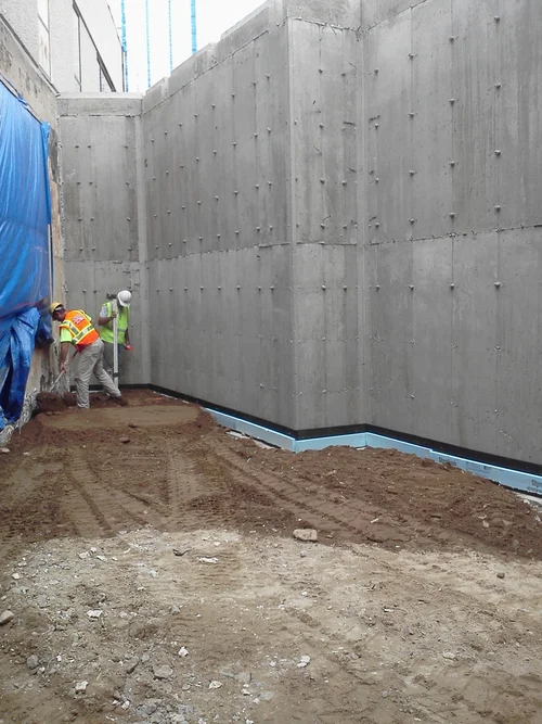 Construction workers installing a concrete wall at a construction site.