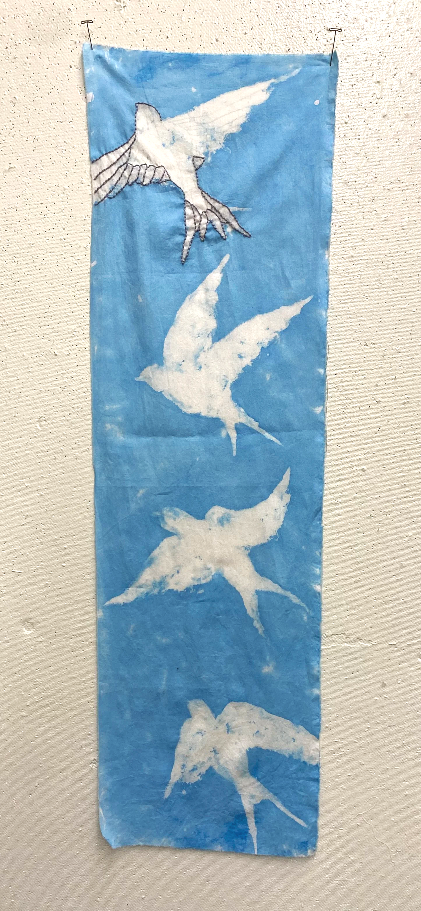 A fabric banner featuring painted or printed images of seabirds in flight, set against a blue sky background.