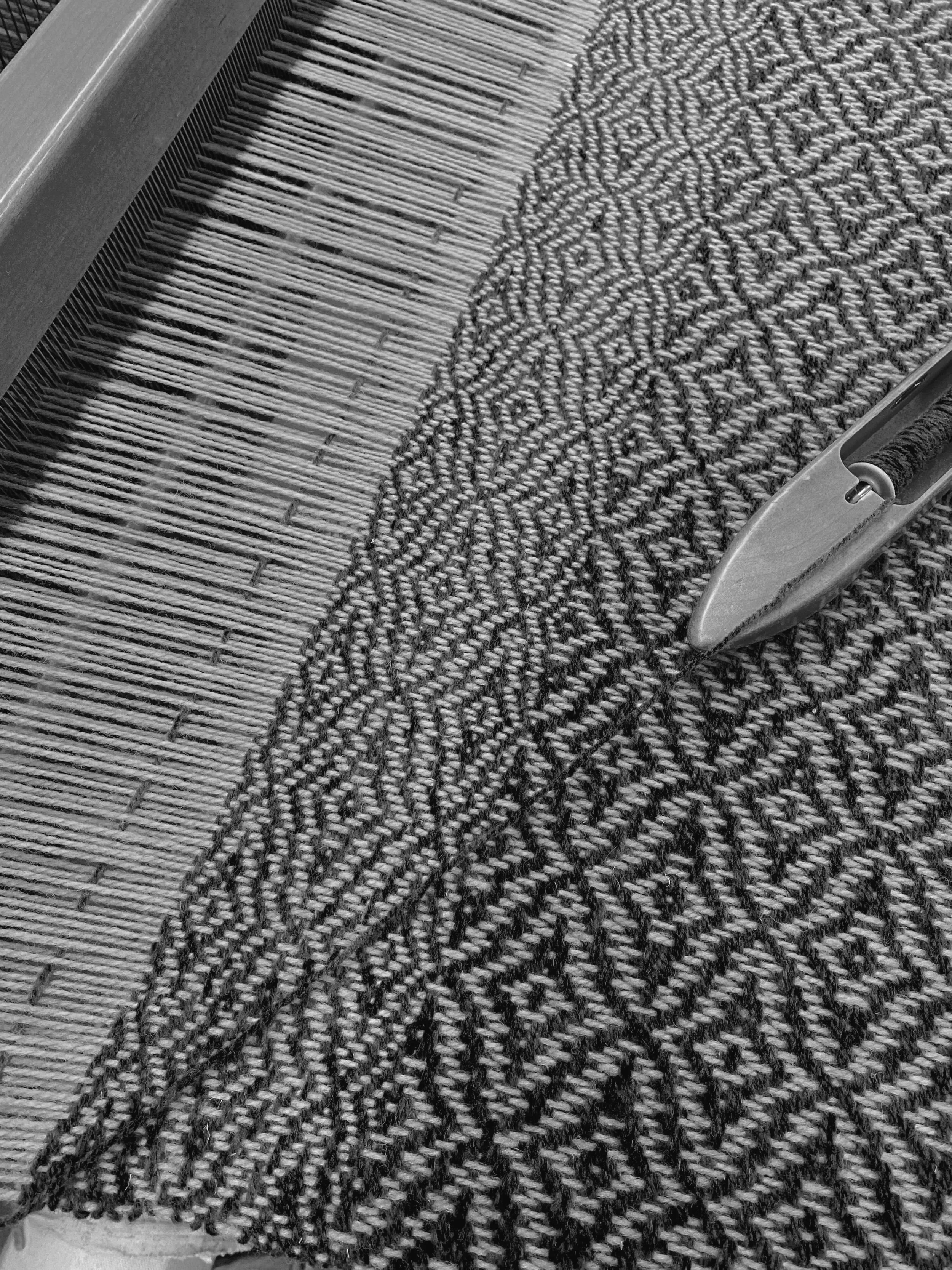 A close-up of a turnstile with a patterned black and gray carpet under it.