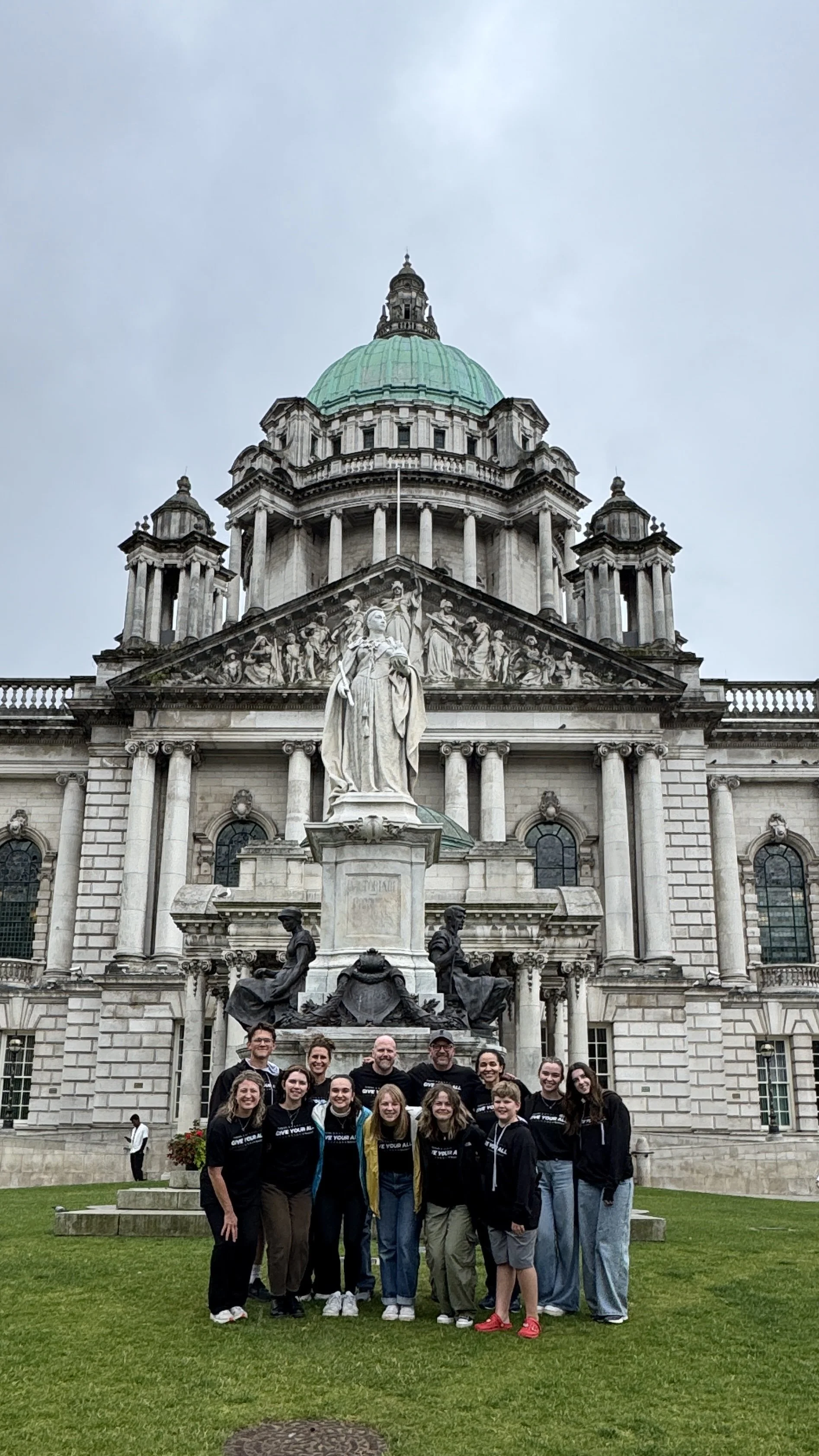 Group of people standing in front of a historic building with a dome and statues.