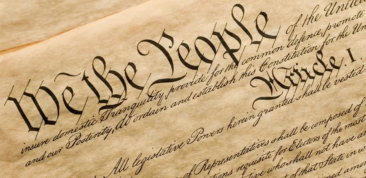 Close-up of the Preamble of the United States Constitution written in ornate cursive calligraphy on aged parchment paper.