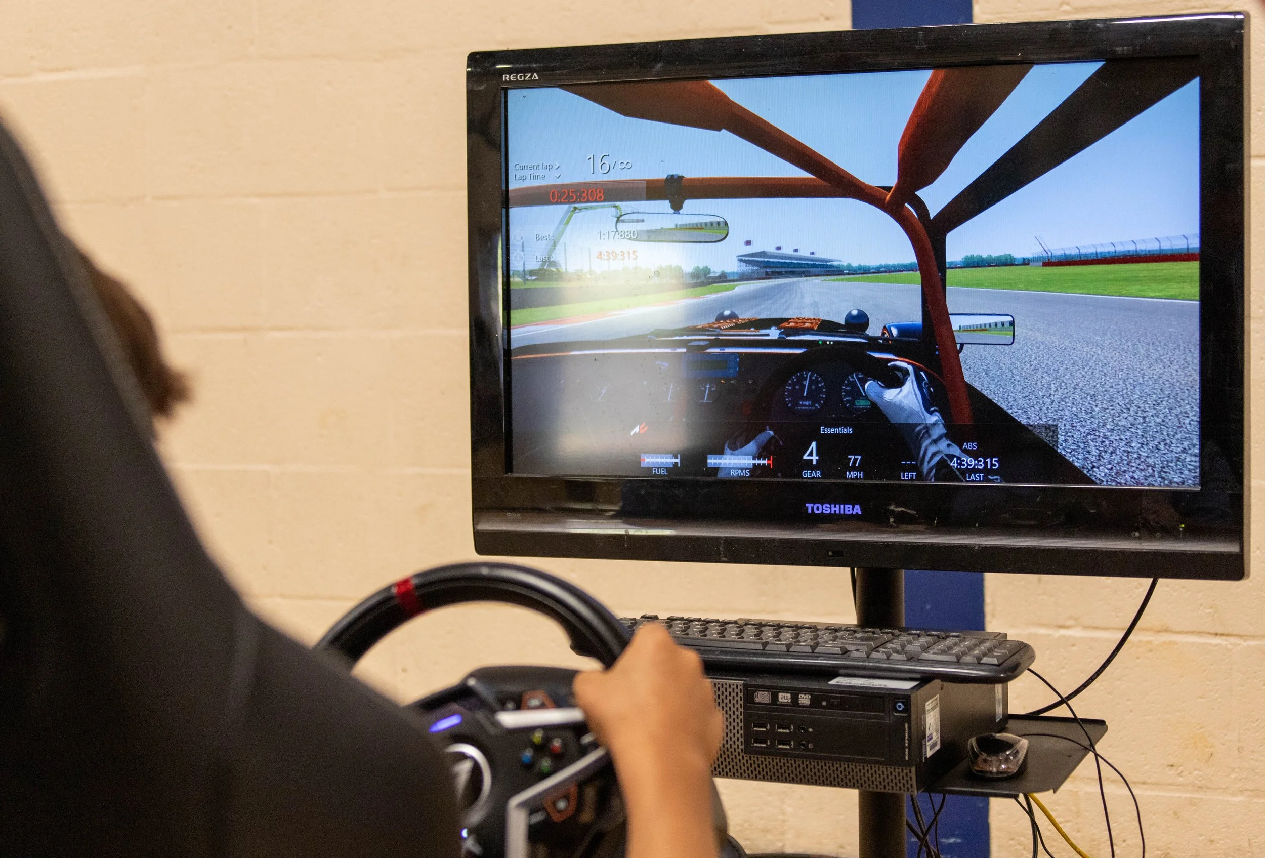 Student driving along a track in a racing simulator with a steering wheel