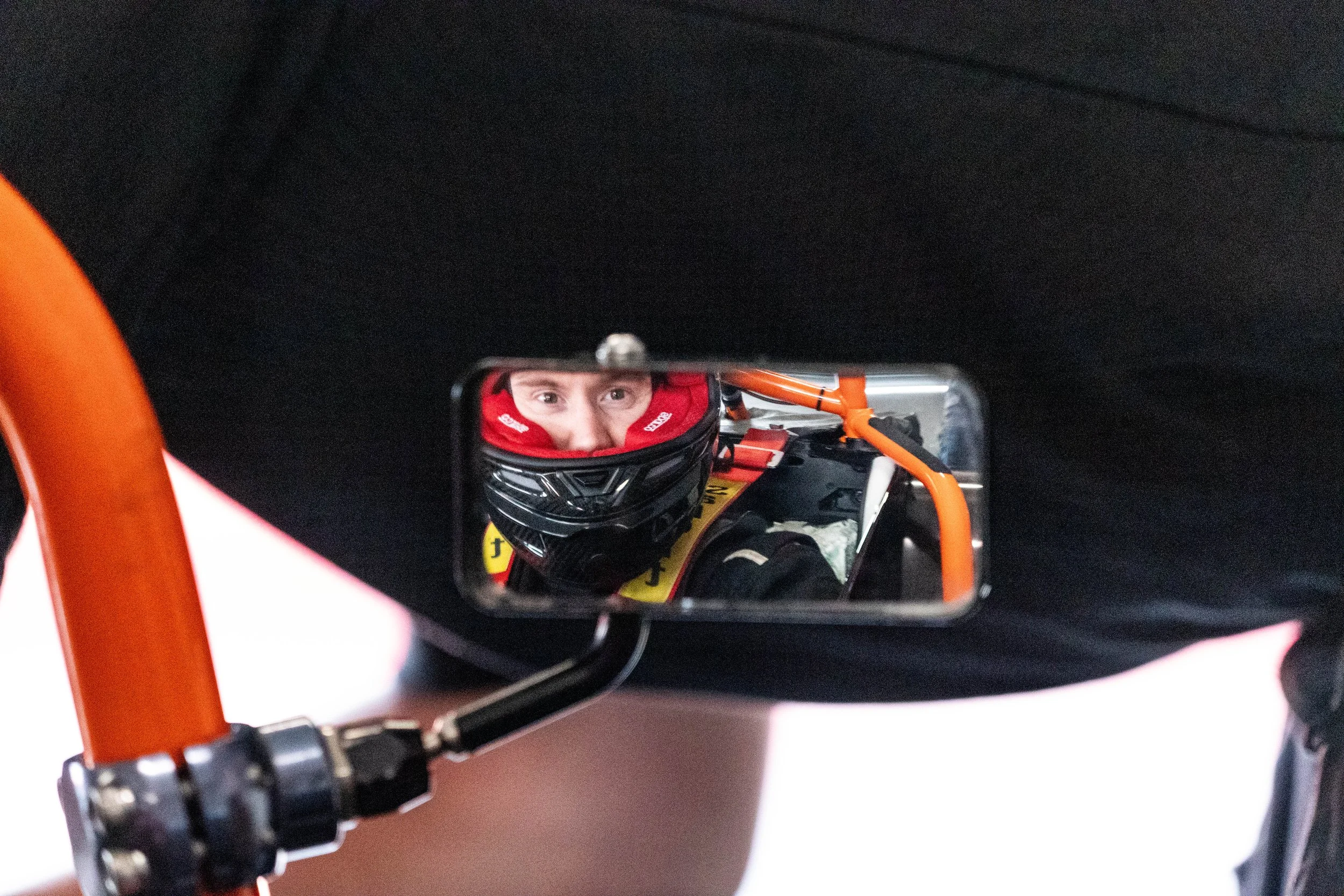 Thomas Horton wearing a helmet, seen through a rearview mirror inside the vehicle, with a focus on the person's eyes.
