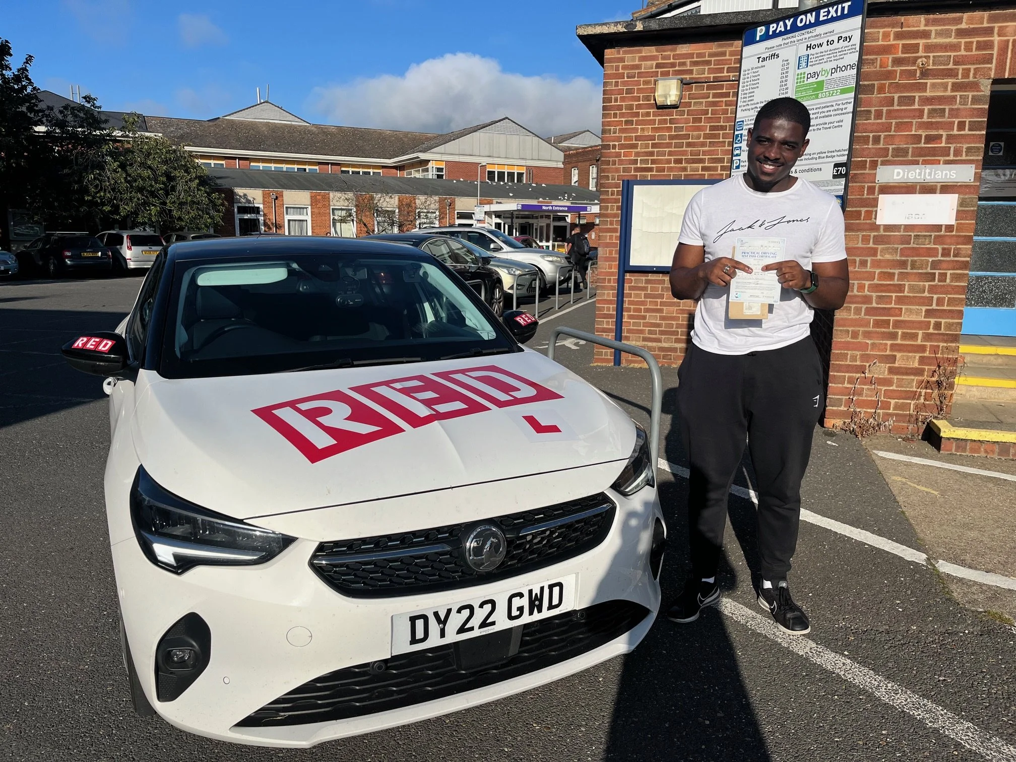 A student driver standing in front of EM Driving School's learner driver car after passing his practical test