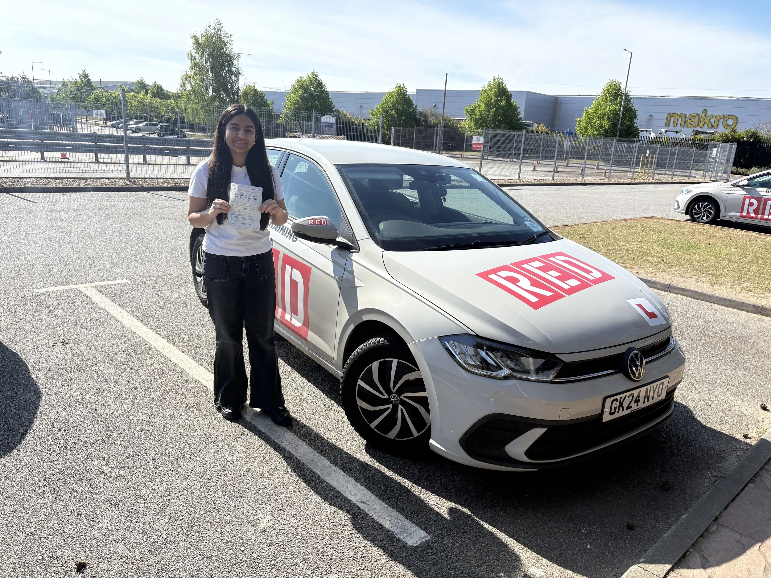 A student driver standing in front of EM Driving School's learner driver car after passing her practical test