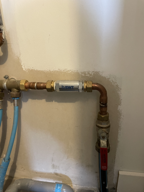 Tuyaux de plomberie mural avec un filtre antirouille, un robinet et un tuyau flexible bleu.