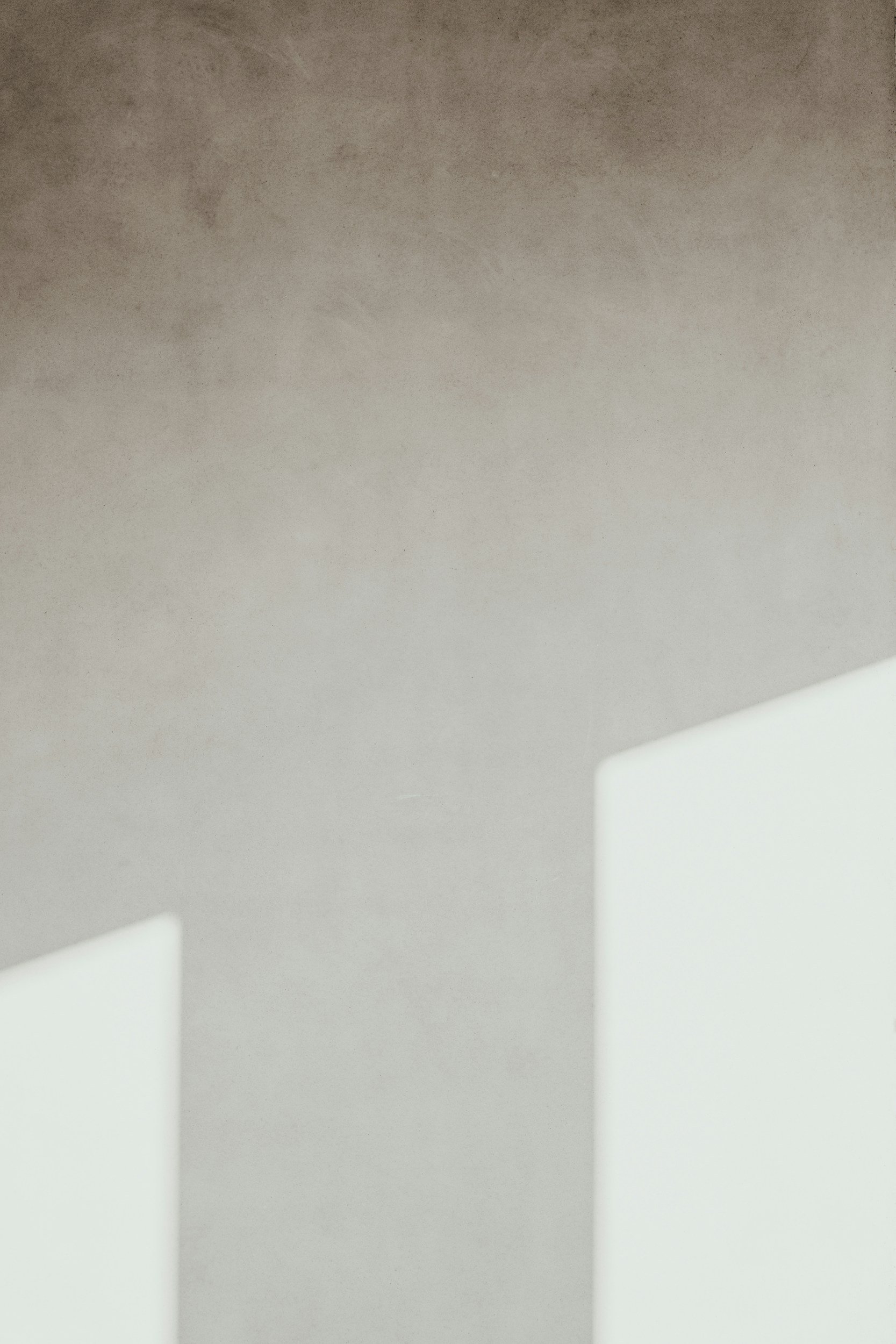 Close-up of a minimalist white structure against a textured gray background.