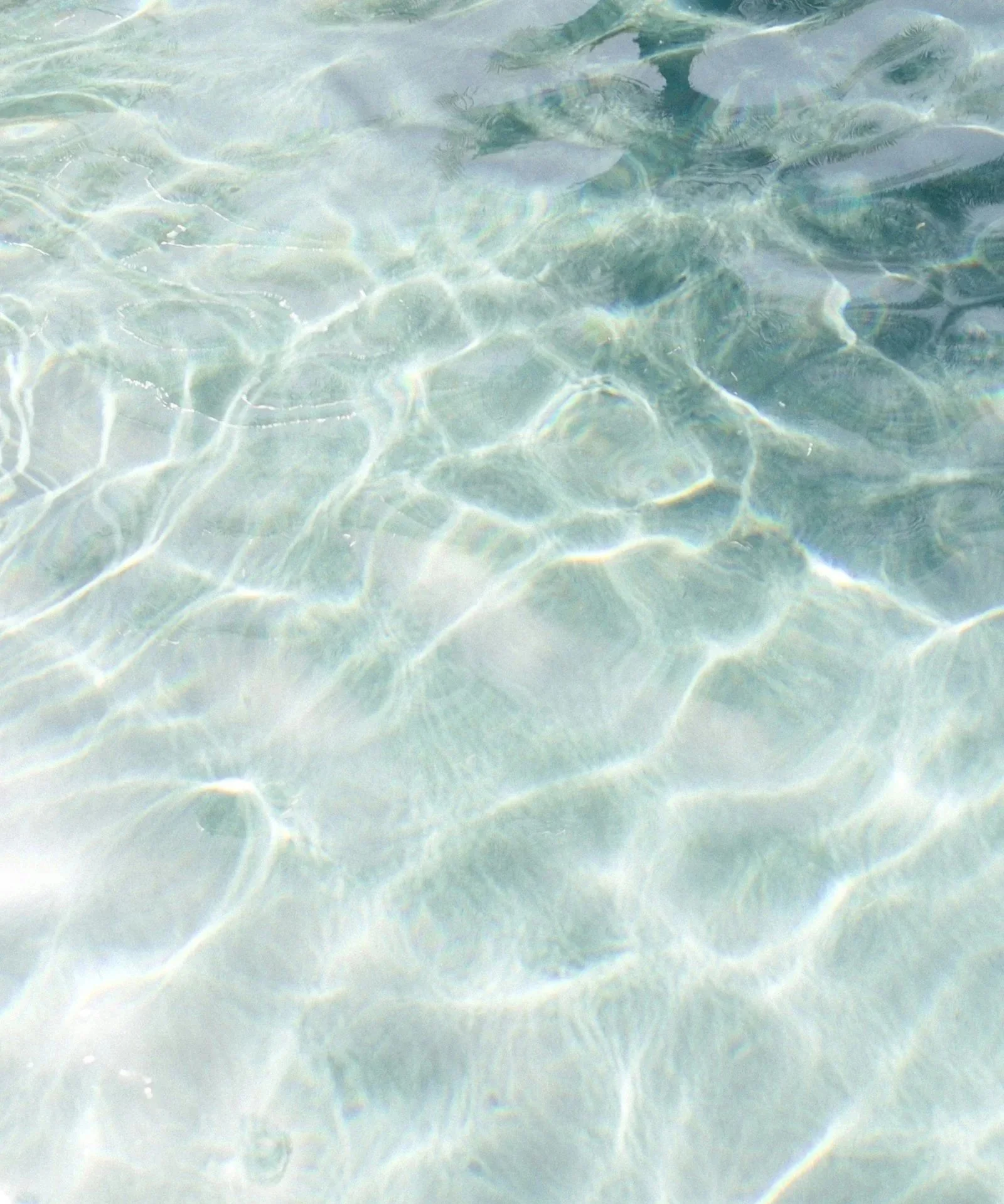 Clear water with sunlight reflections and ripples.