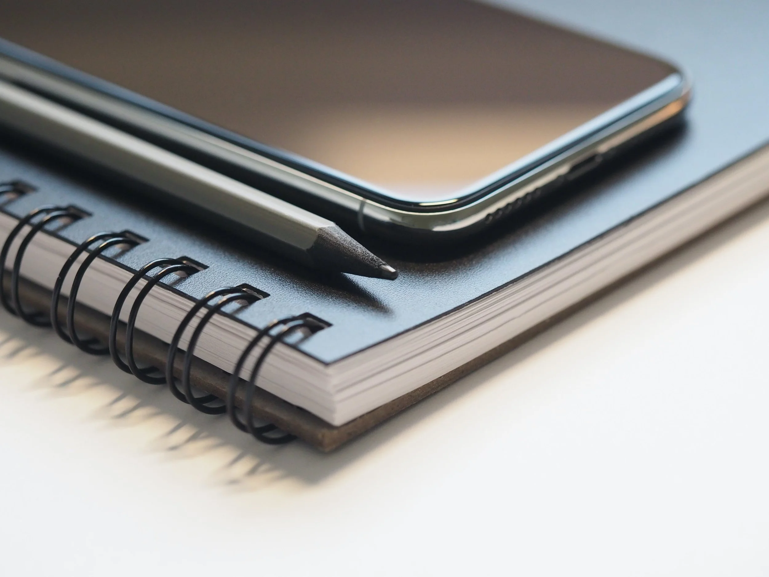A cellphone and pencil sitting on a spiral notebook