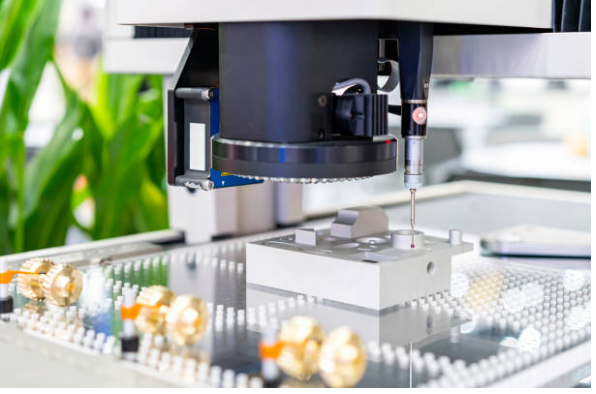 Close-up of a laboratory instrument with a robotic arm conducting a precise operation on a white block, surrounded by electronic components and tools.