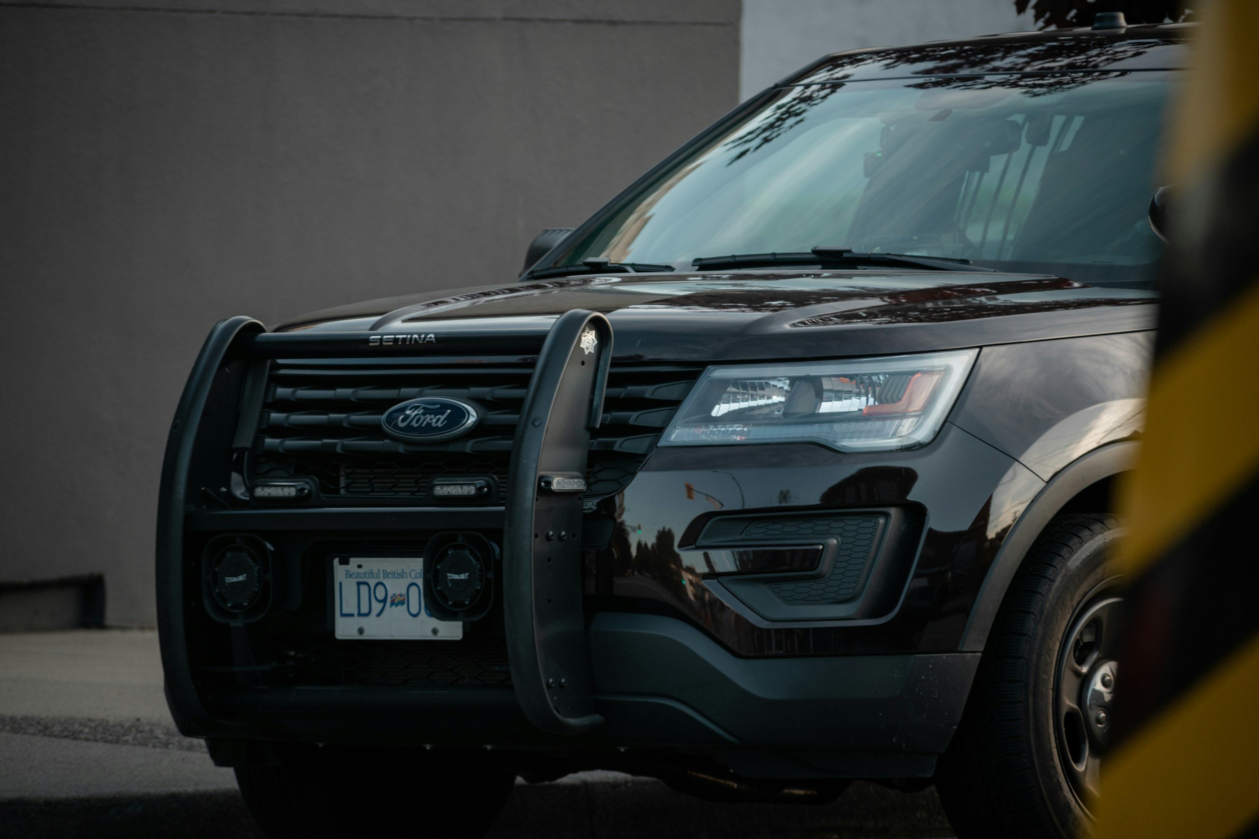 A black Ford police SUV equipped with a push bar and light bar, parked on the street.