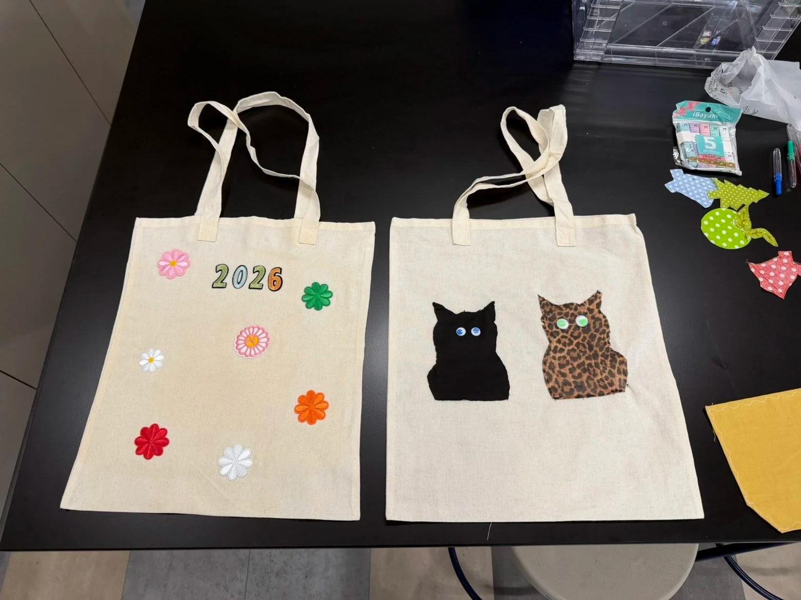 Two finished upcycled tote bags featuring embroidered flowers and appliquéd cat designs made by workshop participants