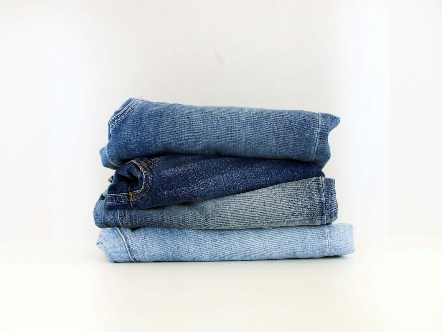 Stack of folded denim jeans in varying shades of blue, ready for donation and upcycling