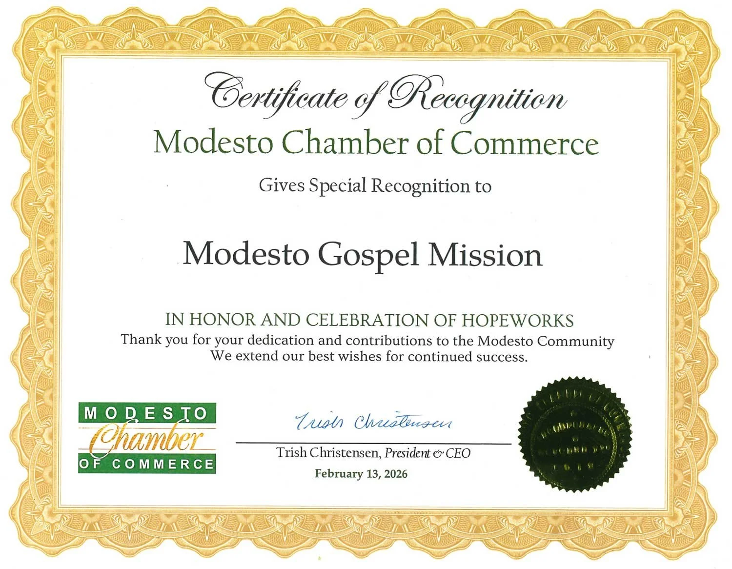 A certificate of recognition awarded to Modesto Gospel Mission by the Modesto Chamber of Commerce, dated February 13, 2026, featuring a gold decorative border and green and black seals.