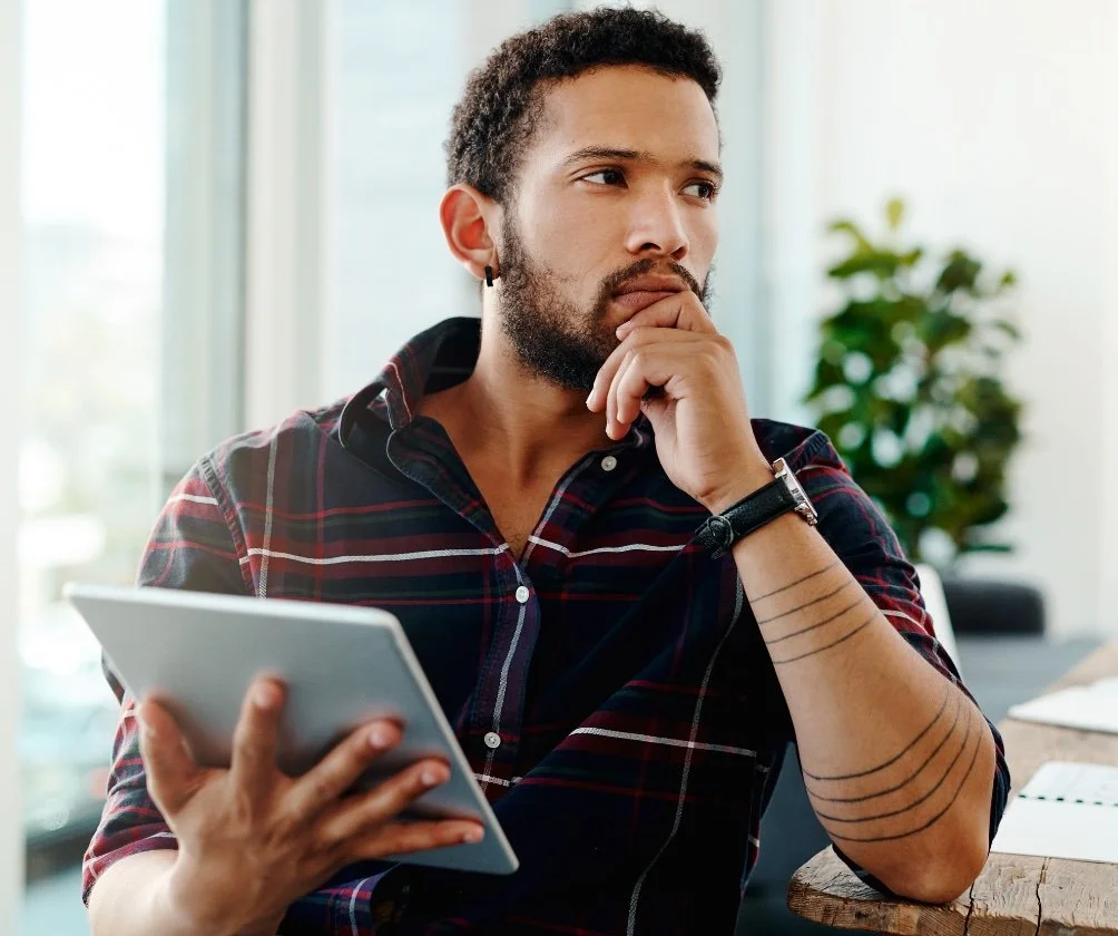 Person holding a tablet and reflecting, representing learning and taking small steps toward better gut health