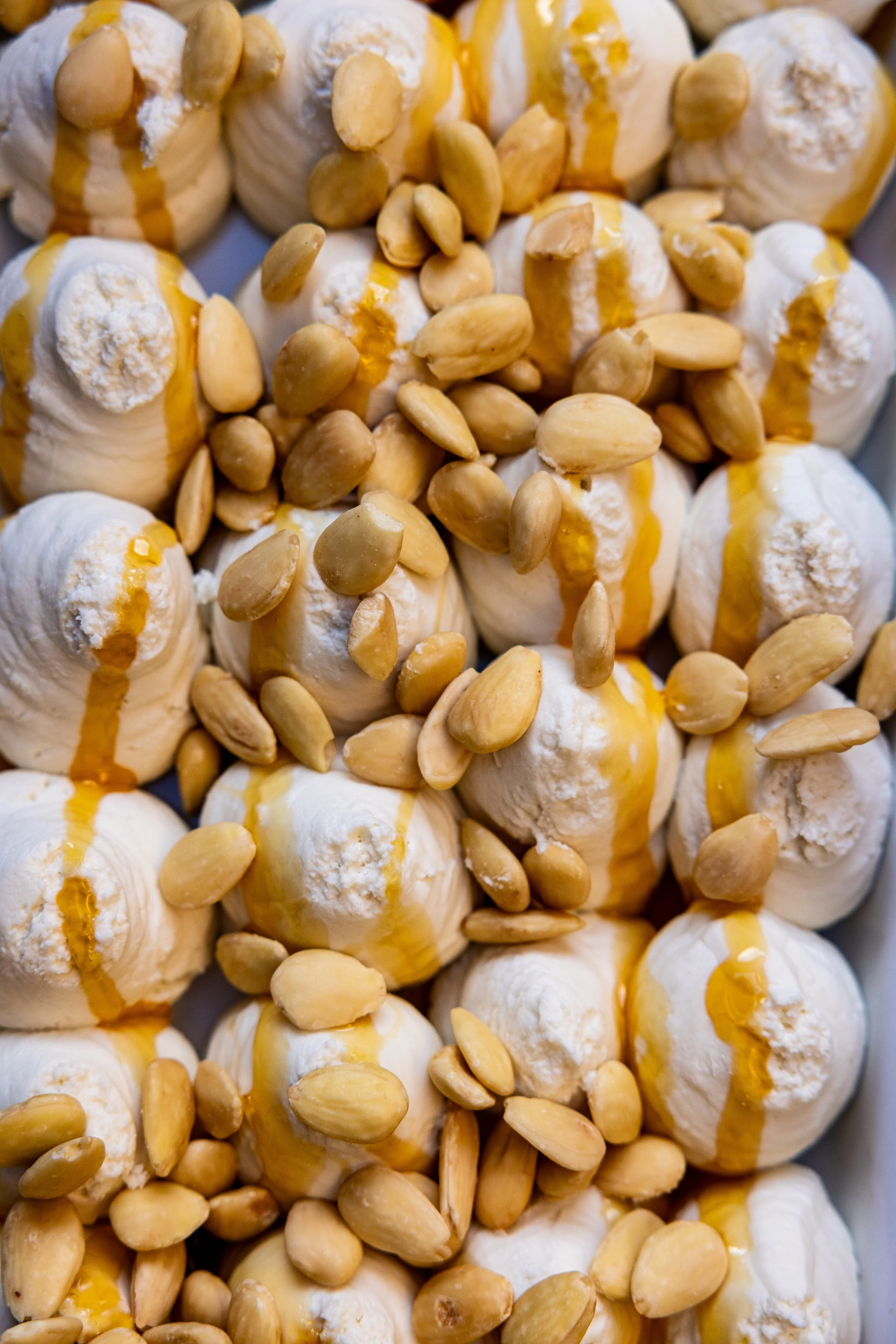 Close-up of vanilla ice cream topped with almonds and drizzled with caramel sauce.