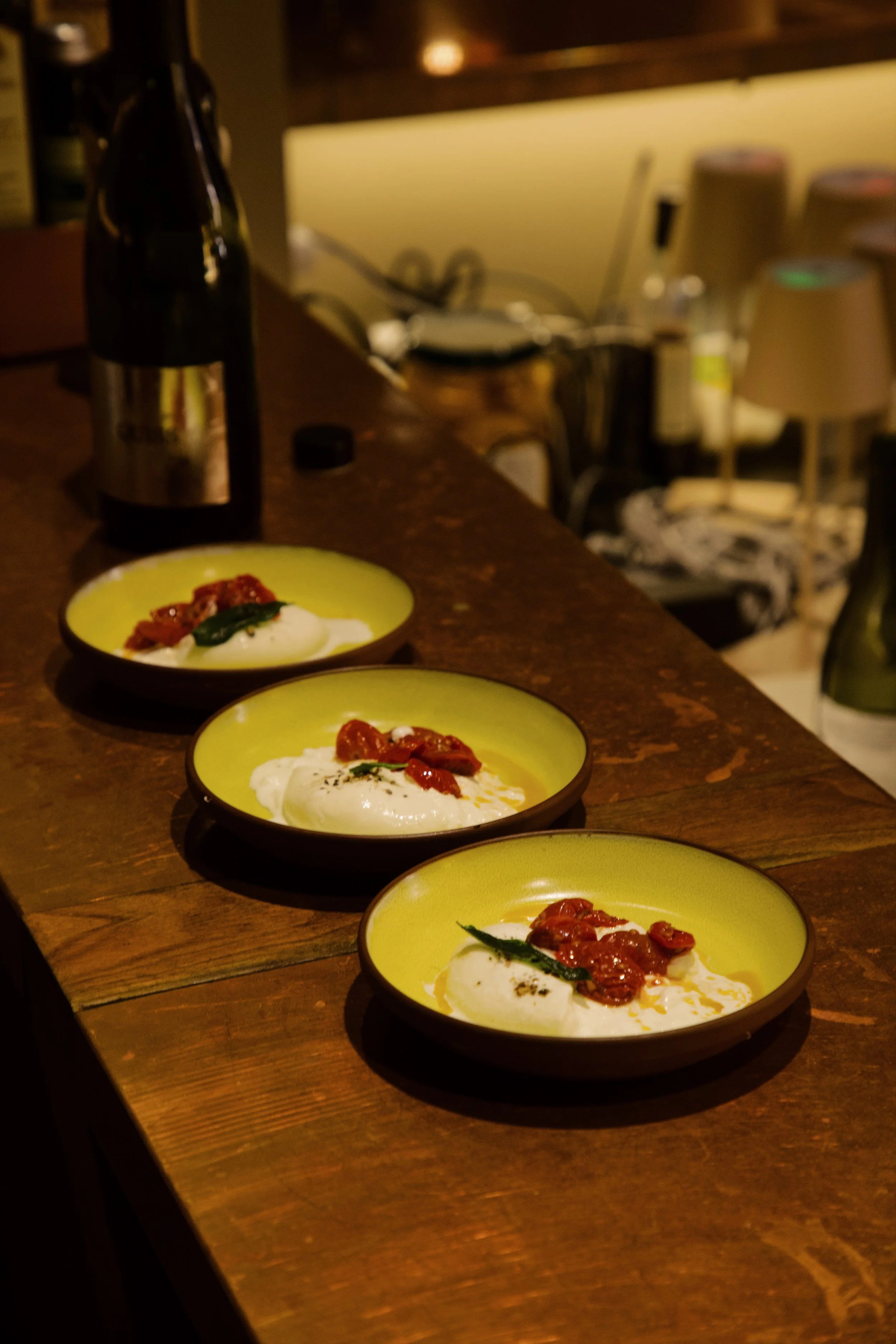 Three small bowls with fresh mozzarella topped with sun-dried tomatoes and herbs at Roscioli's cheese tasting classes