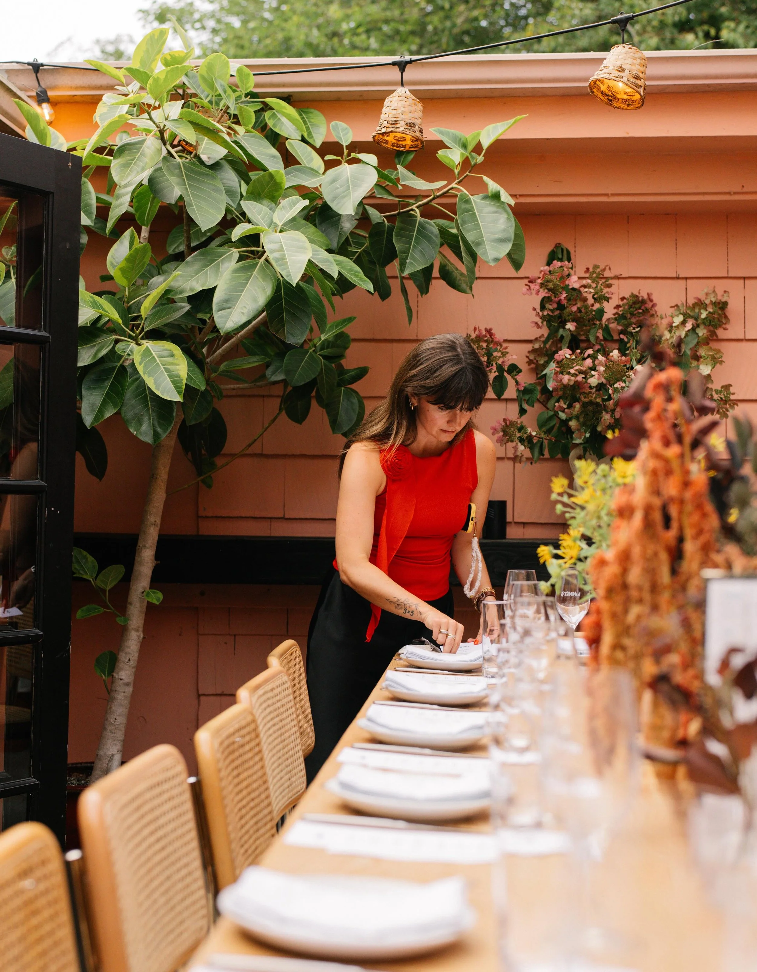 Table being set for a private Italian catering dinner with floral arrangements and place settings.