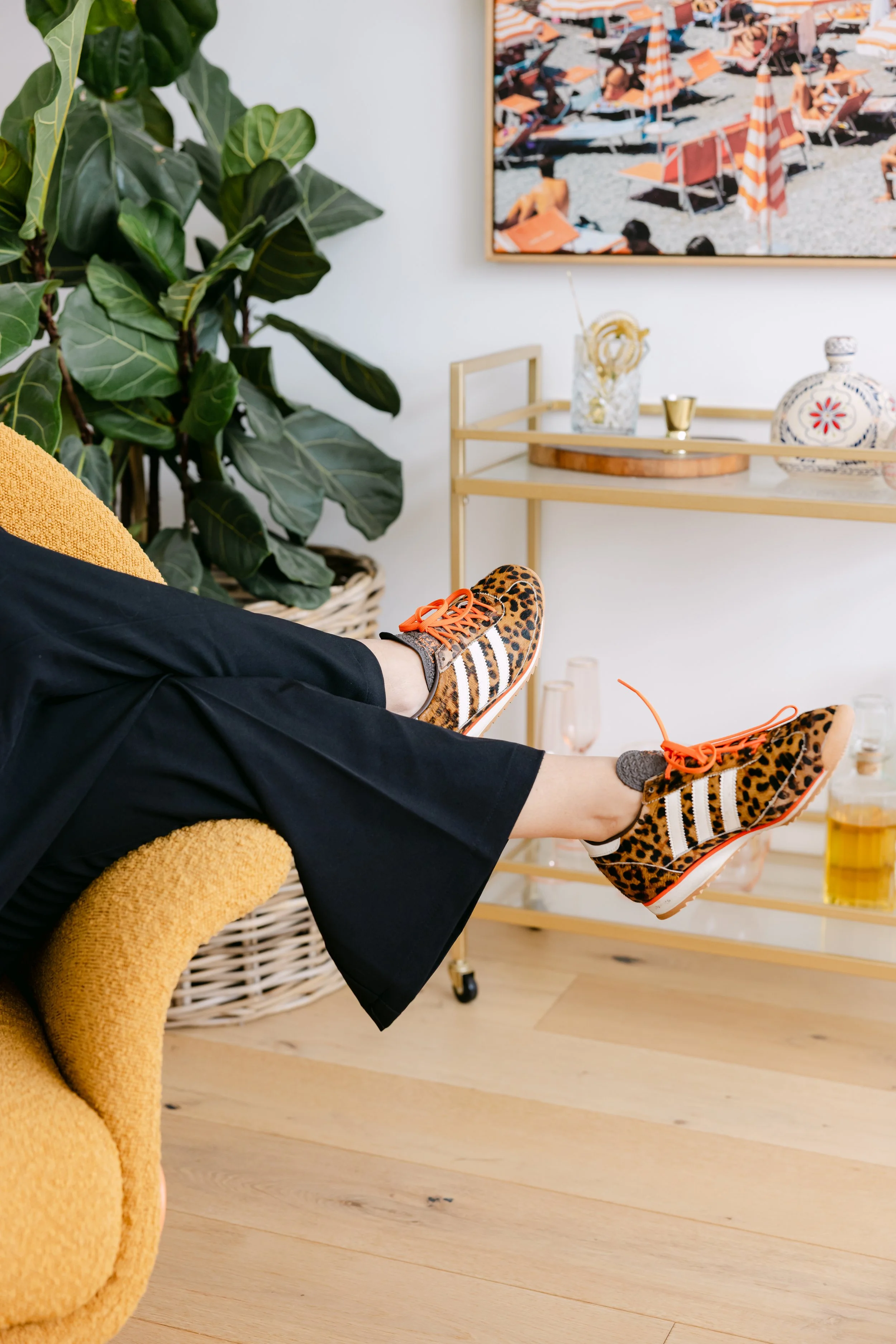 A woman wearing a black off-the-shoulder top taking a selfie with her smartphone, which has a tortoiseshell patterned case, in front of a light background.