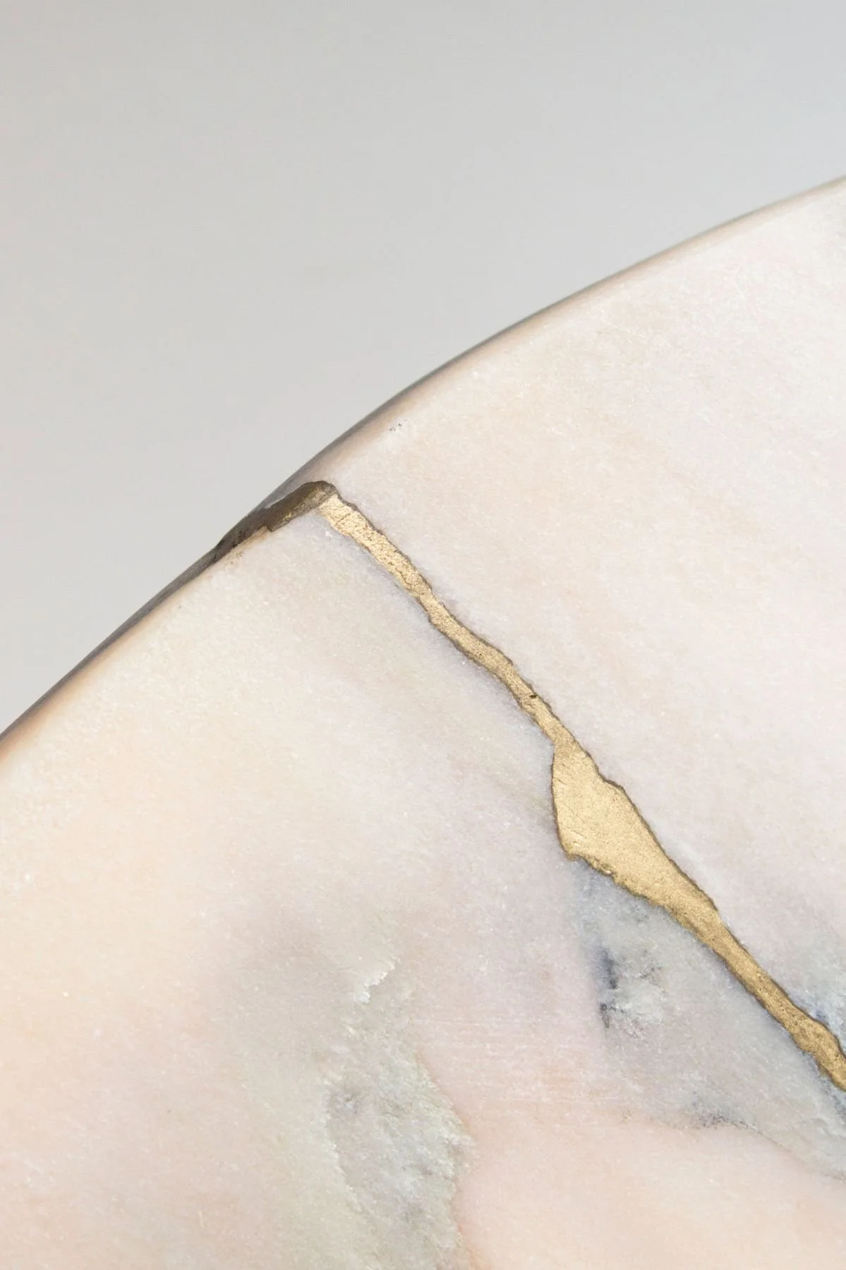 Nahaufnahme einer weißen Marmorplatte mit einer goldenen Metalllinie.