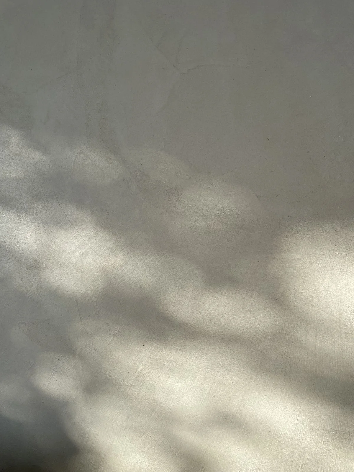 Das Bild zeigt eine Lichtreflexion und Schatten auf einer glatten, hellgrauen Oberfläche.