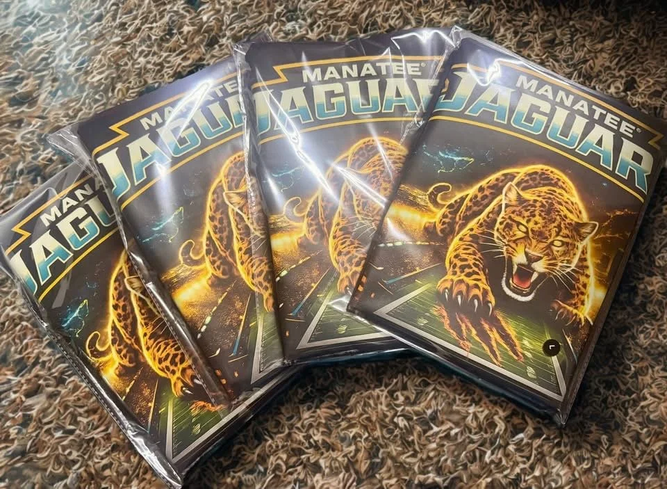 Four sealed packs of 'Manatee Jaguar' trading cards or collectible cards, featuring a glowing, roaring jaguar on the front, placed on a textured surface.