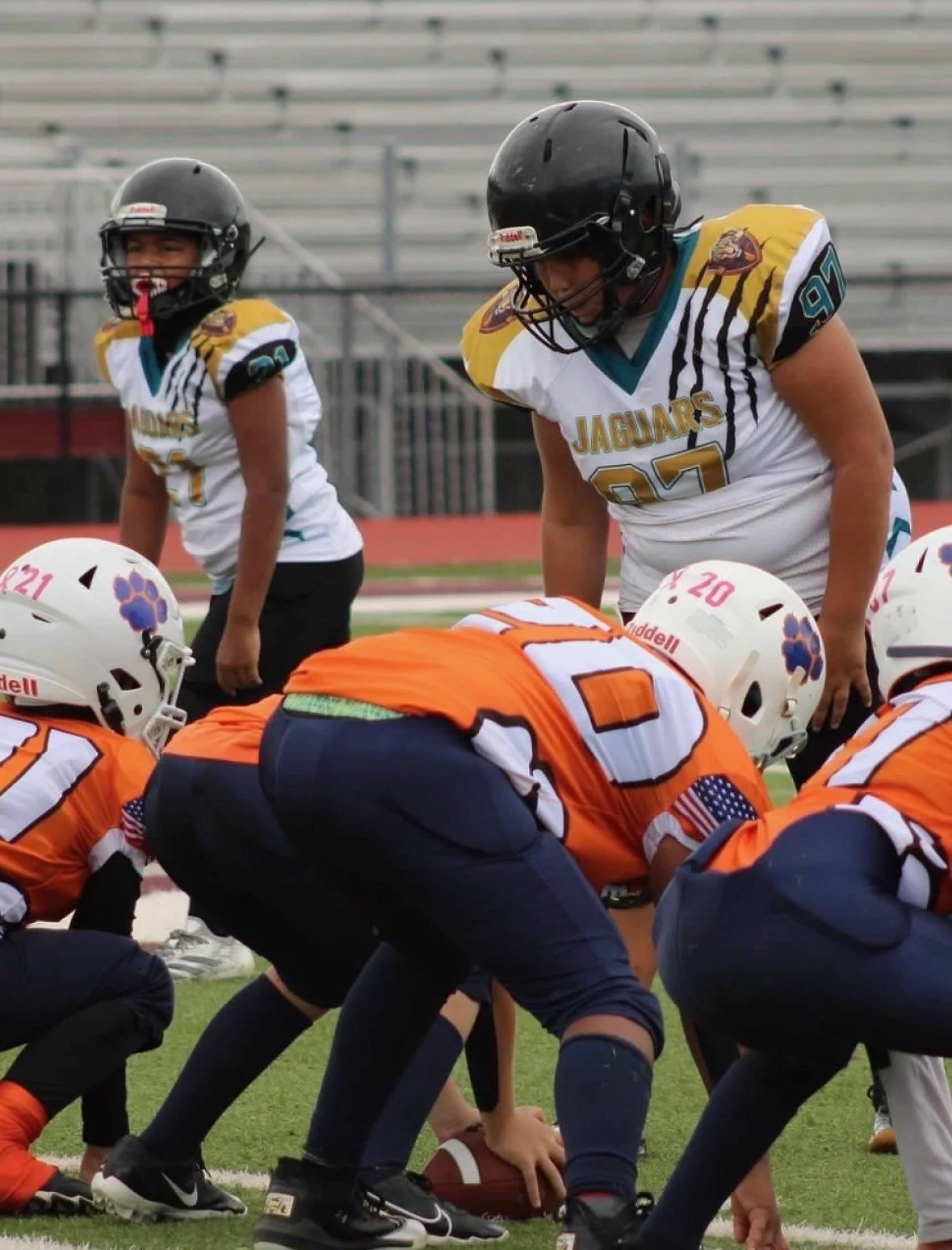American football players in formation on the field, preparing for a play, with players in white jerseys labeled Jaguars and players in orange jerseys.