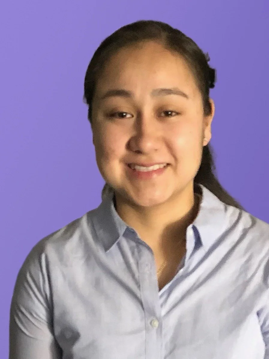 Portrait of a woman smiling, wearing a light colored shirt against a purple background.