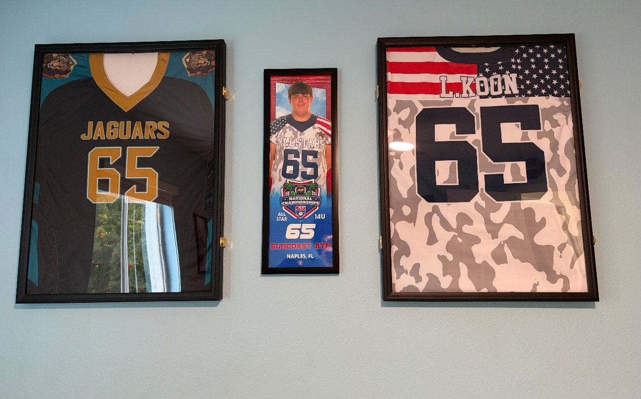 Display of framed sports jerseys, a photograph, and sports memorabilia