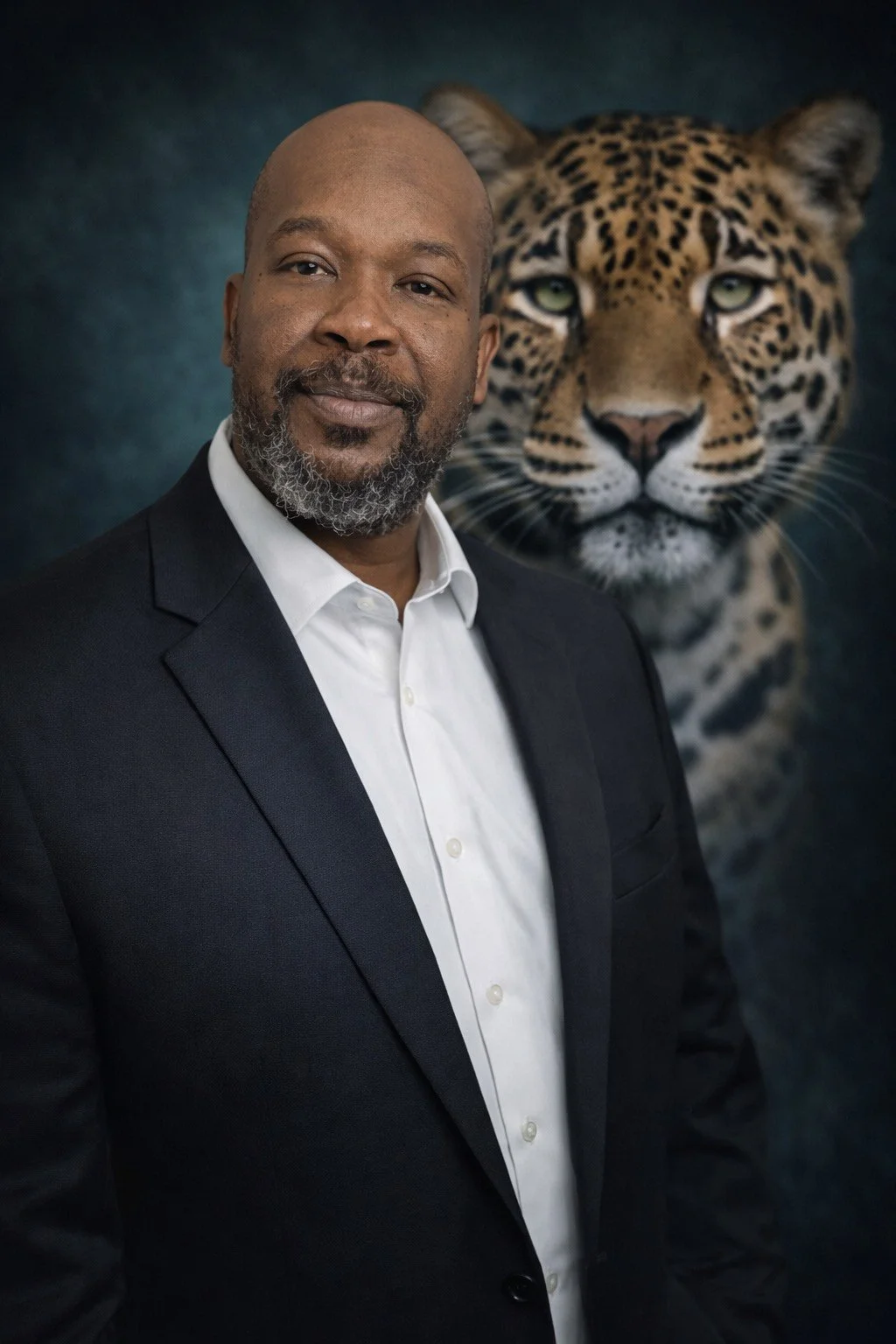 A man in a black suit and white shirt standing in front of a backdrop featuring a large image of a jaguar with piercing green eyes.