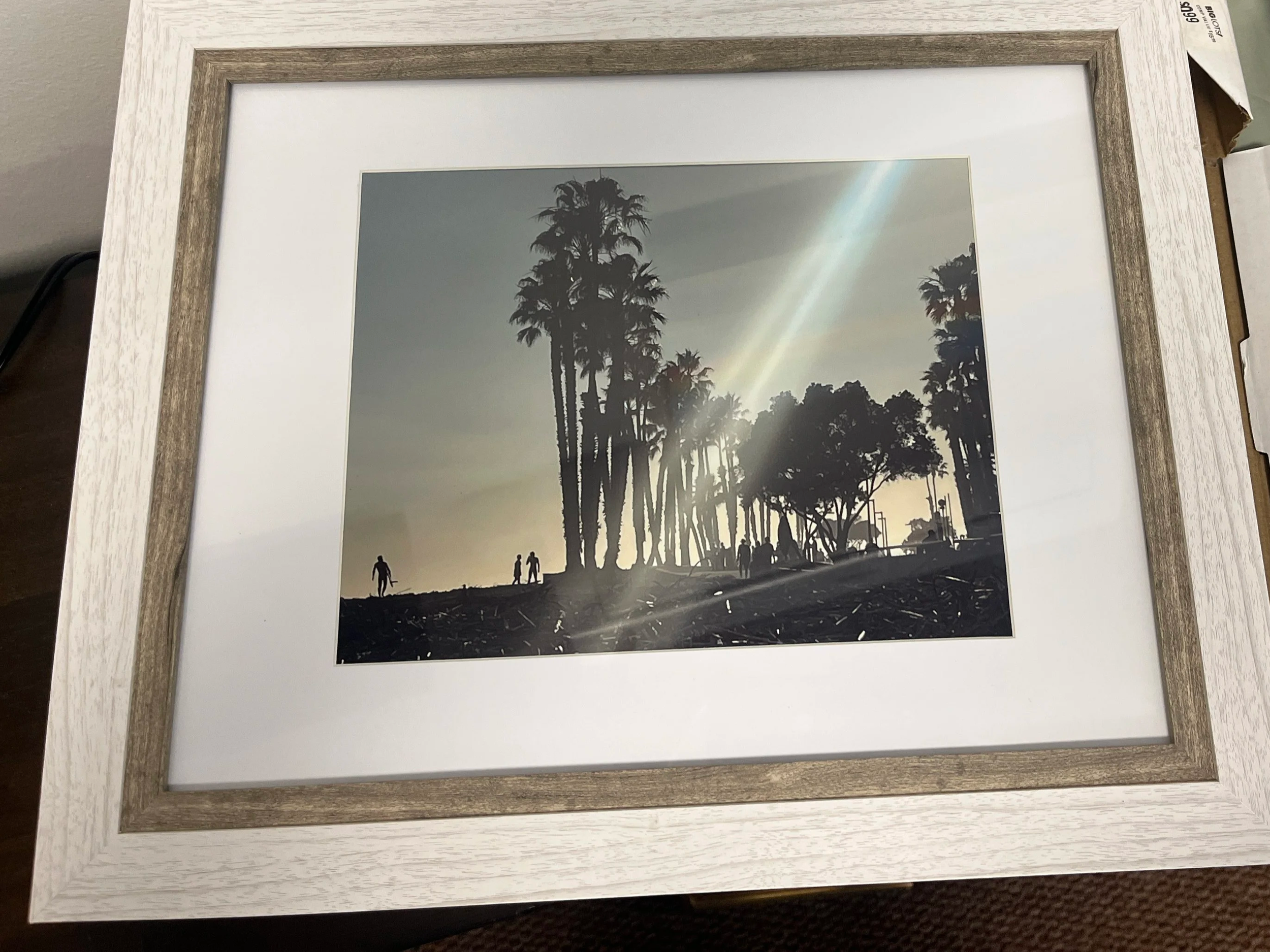 Surfers point, a late afternoon photograph of a beach filled with driftwood, palm trees to the right and surfers on the left coming out of the water.