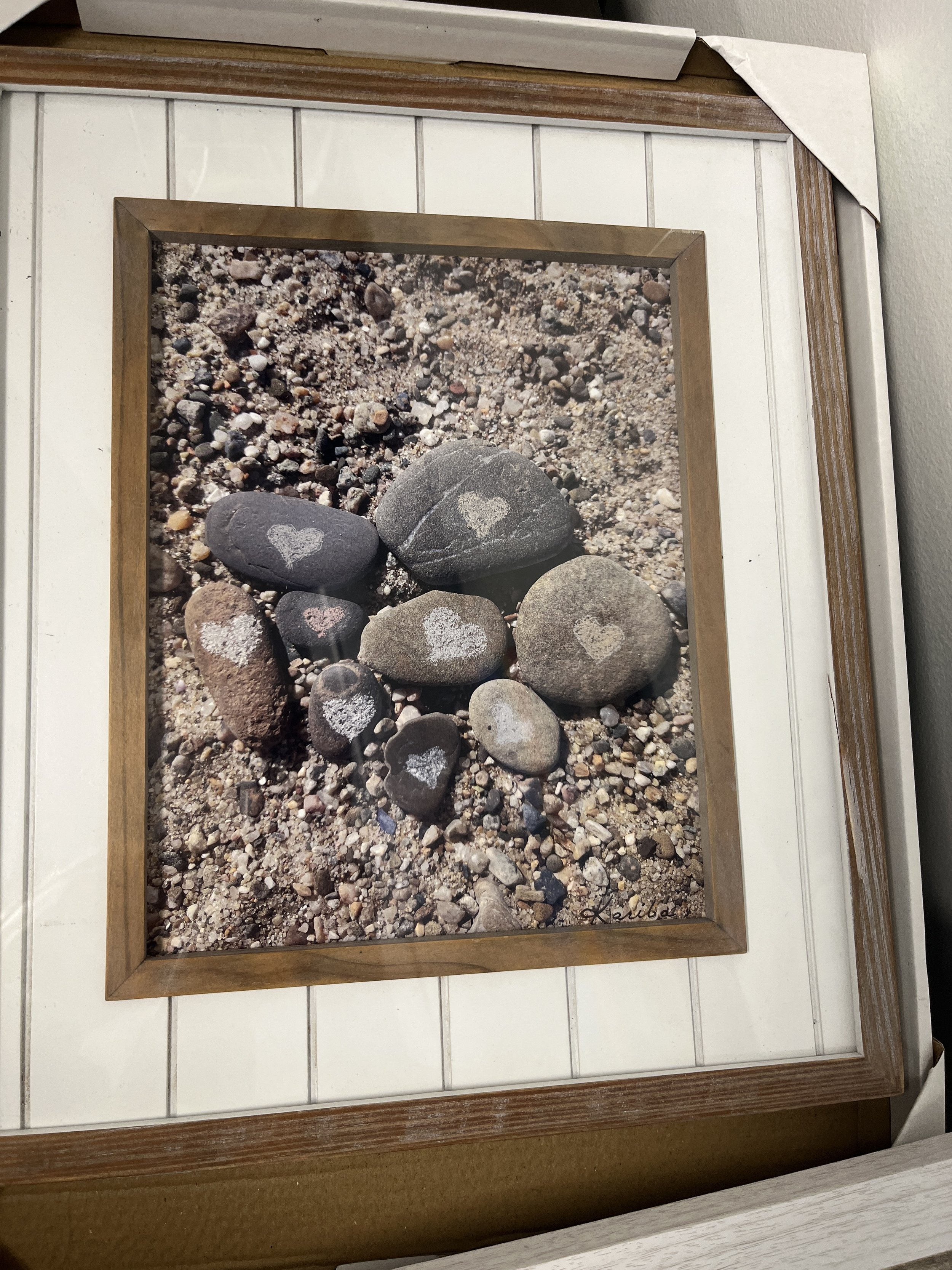 Collection of rocks on sand. Each rock has a heart scratched into the face of it.