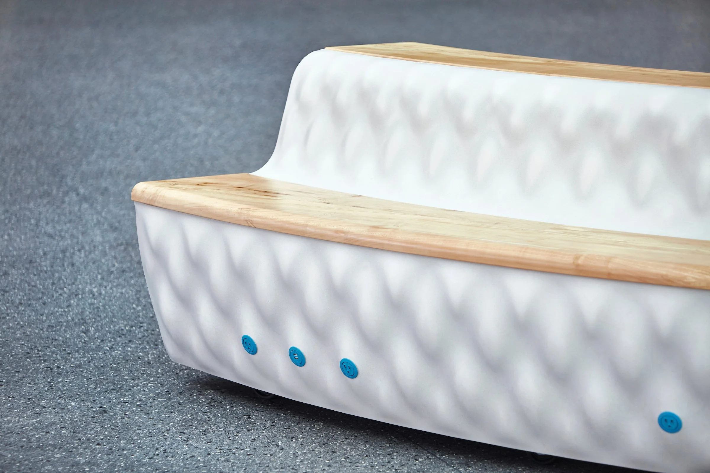 Modern white sofa with wooden armrests and decorative textured fabric, placed on a gray speckled floor.