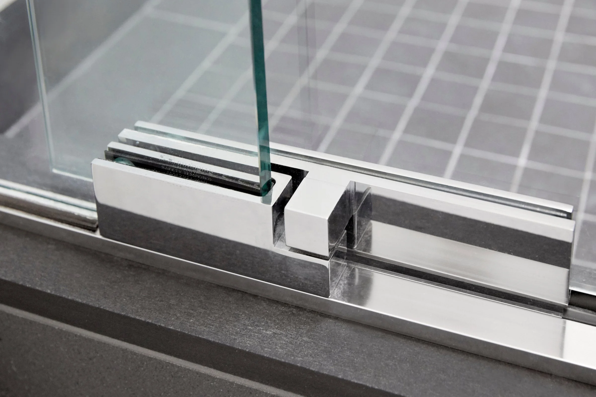 Close-up of a glass door hinge with metal and glass components.
