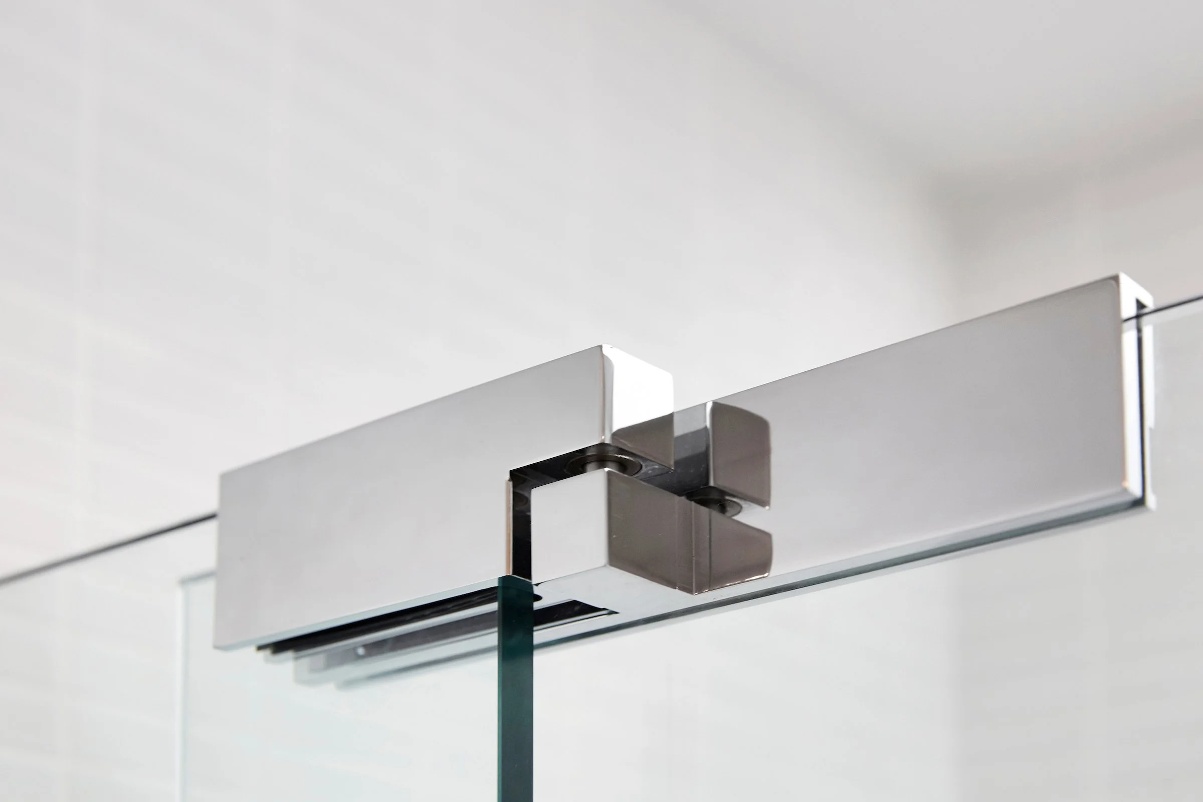 Close-up of a modern glass door hinge with metal brackets